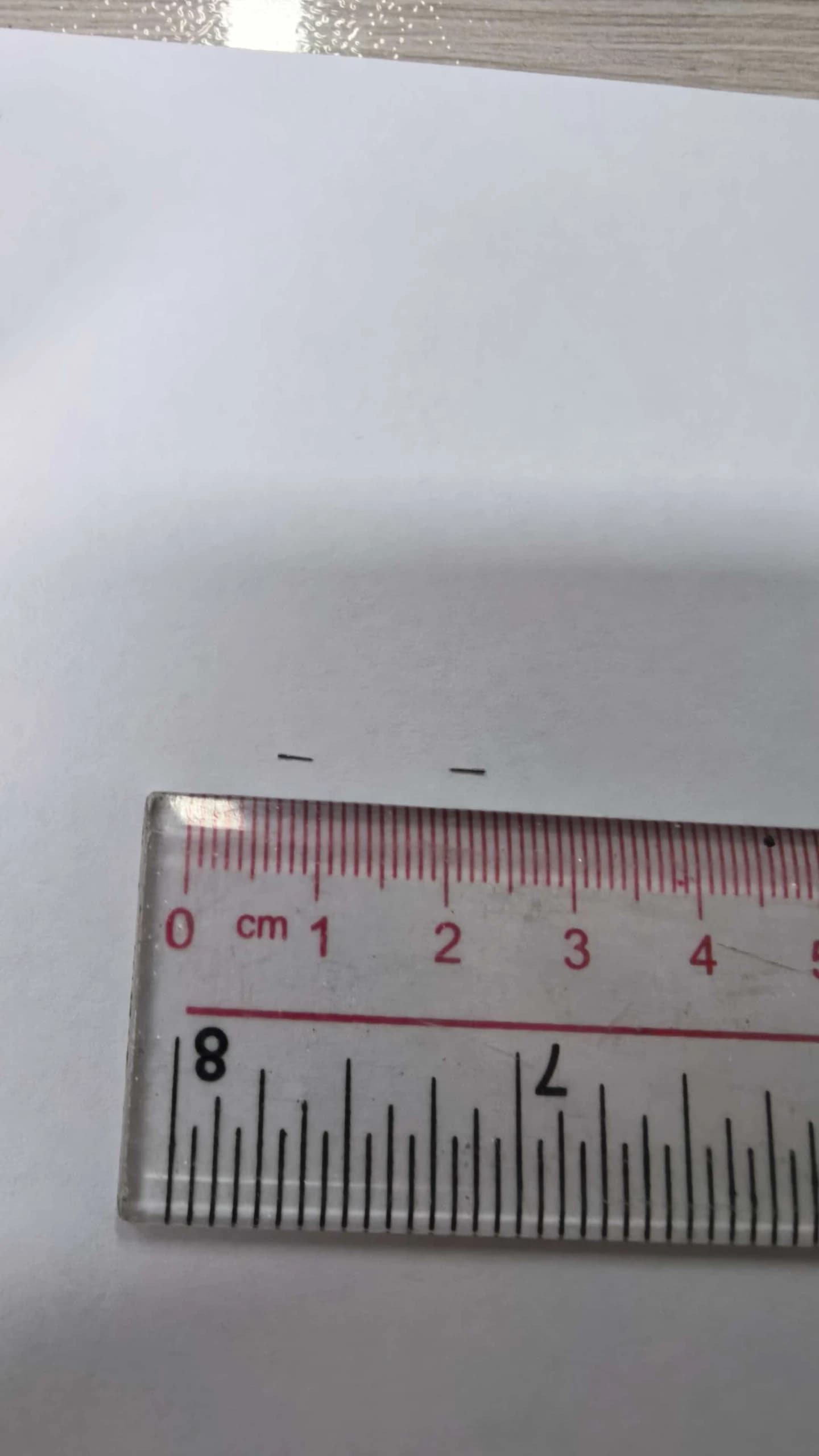 Full original photograph of two tiny components beside a ruler with millimetre divisions